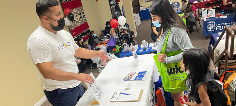 Man talks to parent and child at info table