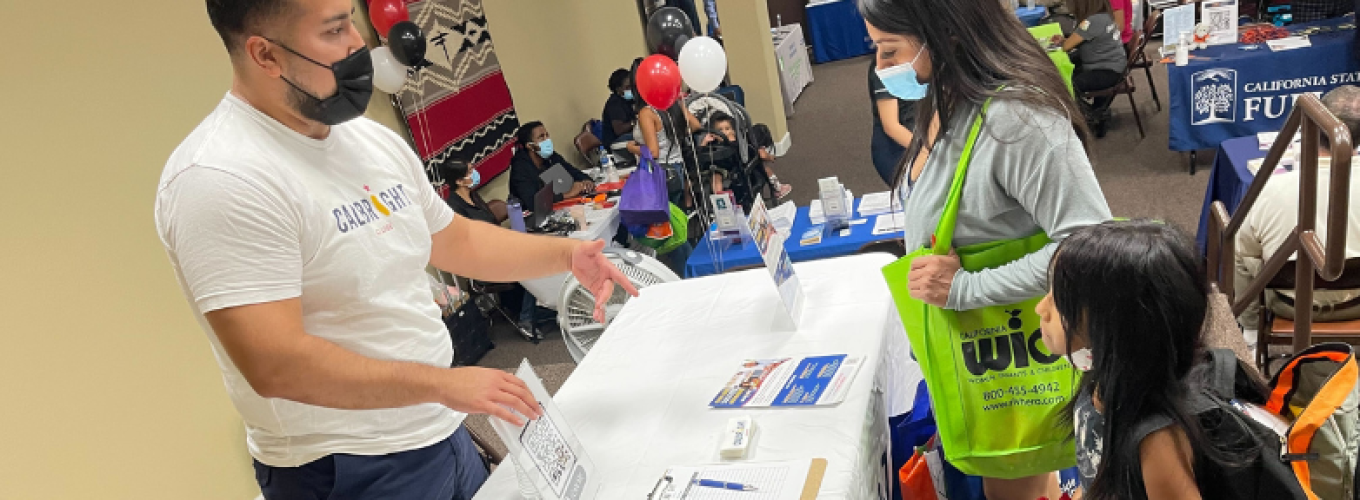 Man talks to parent and child at info table