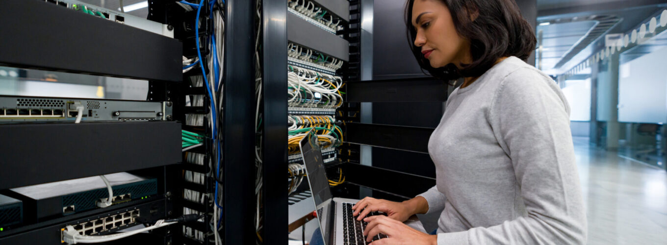 Female IT support technician fixing a network server at an office - technology concepts