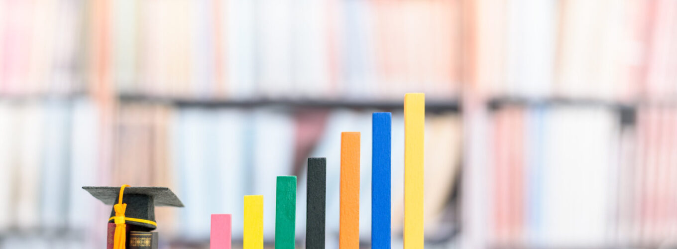 Education and life long learning is the key success, educational concept : Black graduation cap or a mortarboard, textbooks, increasing height color bar graphs with blurred bookshelf background.