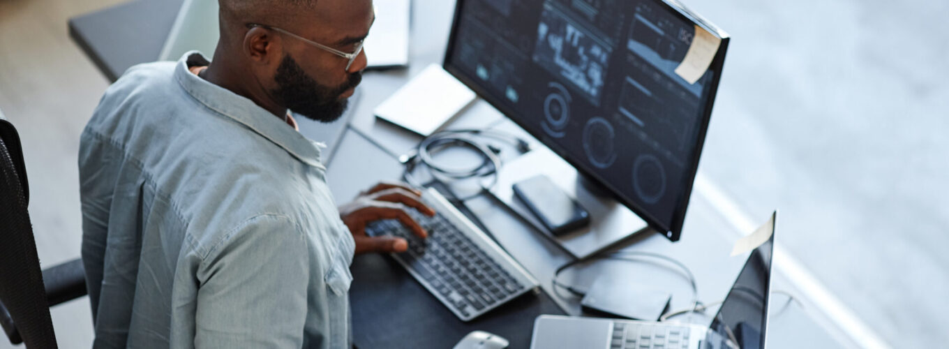 Minimal high angle view at African American IT support working with computers and data systems in office