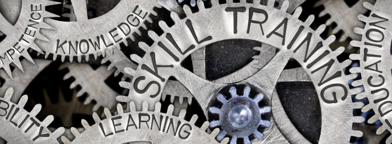 Macro photo of tooth wheel mechanism with SKILL TRAINING, EDUCATION, LEARNING, ABILITY, KNOWLEDGE and COMPETENCE words imprinted on metal surface