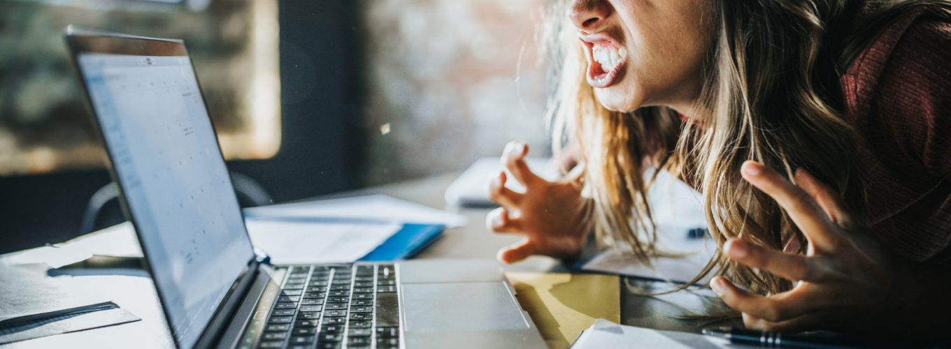 Angry freelance worker feeling displeased after reading an e-mail on a computer.