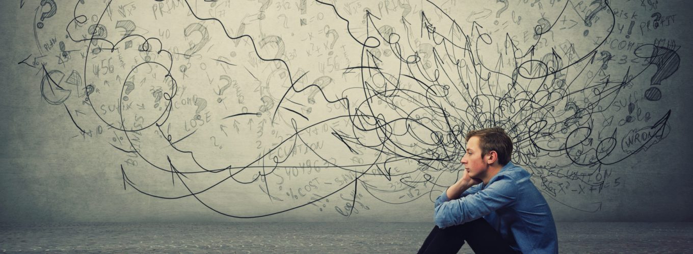 Upset and tired boy teenager sitting on the floor keeps hand to cheek looking thoughtfully and hopeless. Stressed student guy feels emotional discomfort, anxiety and mental health problems.