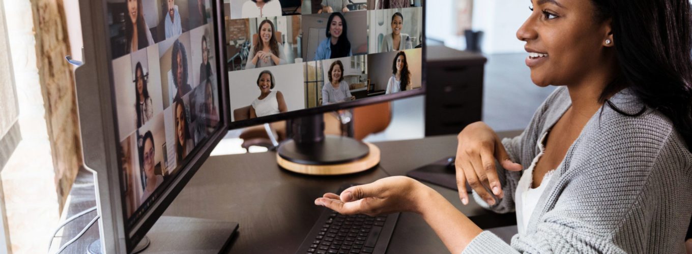 The attractive mid adult woman teleconferences to meet with her diverse colleagues.  She is social distancing due to the coronavirus epidemic.