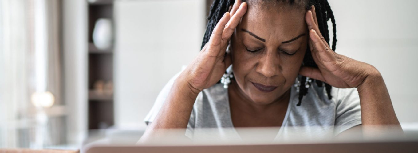 Mature woman with headache in front of laptop at home