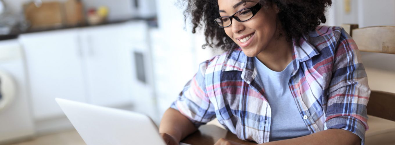 Smiling woman with eyeglasses using laptop at home.